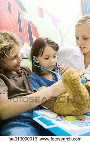 Stock Image - Boy and girl playing doctor with teddy bear. Fotosearch