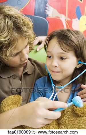 Stock Photography - Boy and girl playing doctor with teddy bear. Fotosearch