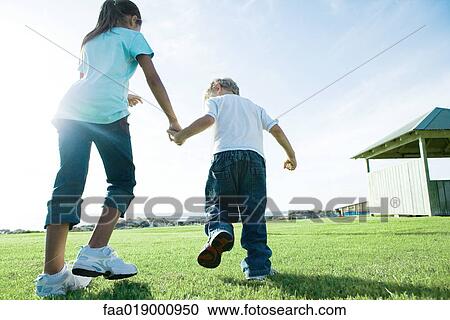 Boy and girl walking across grass View Large Photo Image Stock Image - Boy and girl walking across grass. Fotosearch