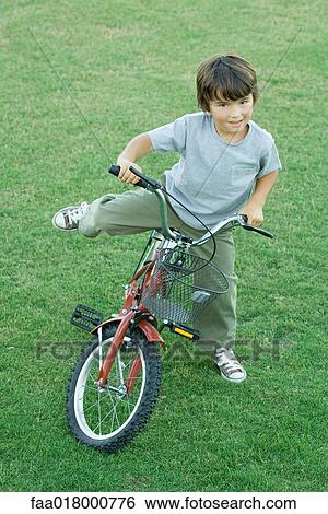 Boy getting on bike, on grass, high angle view, full length View Large Photo Image Stock Photograph - Boy getting on bike, on grass, high angle view, full length. Fotosearch