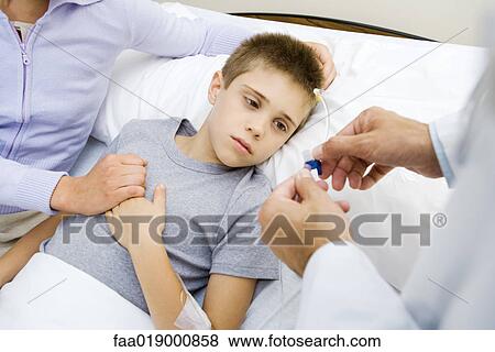 Stock Photo - Boy having IV drip adjusted in hospital. Fotosearch