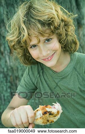 Boy holding grilled chicken leg, smiling at camera, portrait View Large Photo Image Stock Photo - Boy holding grilled chicken leg, smiling at camera, portrait. Fotosearch