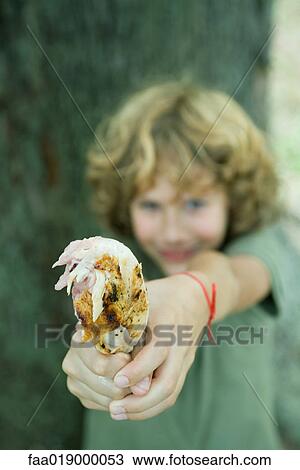 Boy holding out grilled chicken leg View Large Photo Image Stock Image - Boy holding out grilled chicken leg. Fotosearch