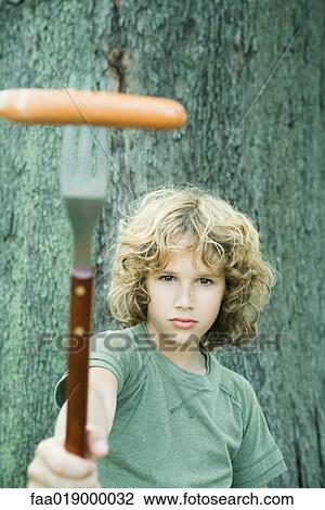 Boy holding up hot dog on fork View Large Photo Image Stock Image - Boy holding up hot dog on fork. Fotosearch