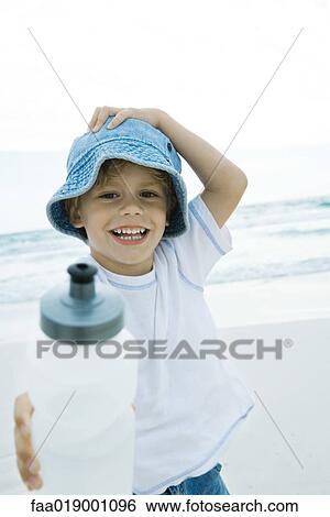 Boy holding up water bottle on beach View Large Photo Image Stock Photograph - Boy holding up water bottle on beach. Fotosearch