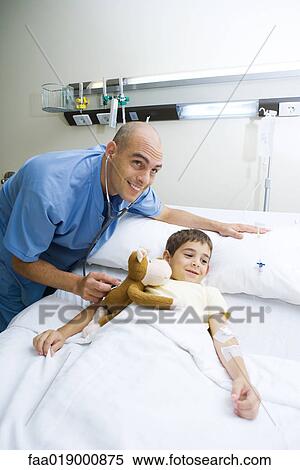 Boy lying in hospital bed, doctor holding stethoscope to stuffed monkey View Large Photo Image Stock Photography - Boy lying in hospital bed, doctor holding stethoscope to stuffed monkey. Fotosearch