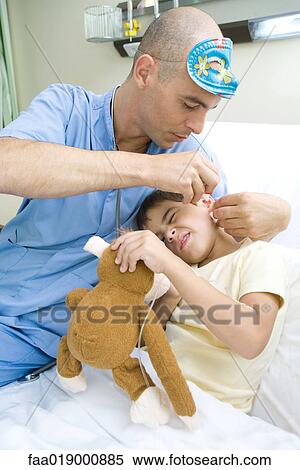 Boy lying in hospital bed, holding stuffed animal while doctor puts drops into boy's ear View Large Photo Image Stock Photography - Boy lying in hospital bed, holding stuffed animal while doctor puts drops into boy's ear. Fotosearch