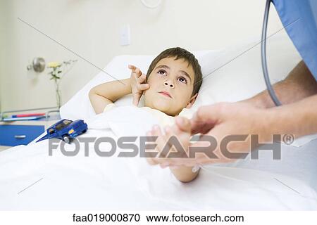 Boy lying in hospital bed, looking up at doctor View Large Photo Image Stock Image - Boy lying in hospital bed, looking up at doctor. Fotosearch