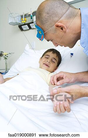 Boy lying in hospital bed, nurse adjusting IV View Large Photo Image Stock Image - Boy lying in hospital bed, nurse adjusting IV. Fotosearch