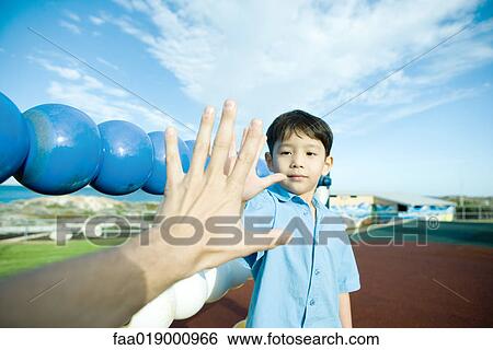 Stock Photograph - Boy on playground, holding out hand to adult hand. Fotosearch