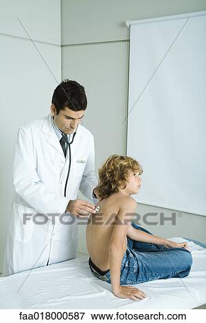 Boy sitting on examination table, doctor holding stethoscope to back View Large Photo Image Stock Photo - Boy sitting on examination table, doctor holding stethoscope to back. Fotosearch