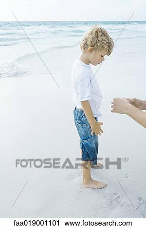 Boy standing on beach with parent View Large Photo Image Stock Image - Boy standing on beach with parent. Fotosearch