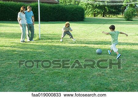 Stock Image - Boys playing soccer while parents watch. Fotosearch