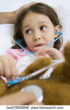Child holding toy stethoscope to teddy bear, talking to man View Large Photo Image Stock Photo - Child holding toy stethoscope to teddy bear, talking to man. Fotosearch