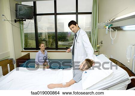 Picture - Child lying in hospital bed, doctor standing by side. Fotosearch