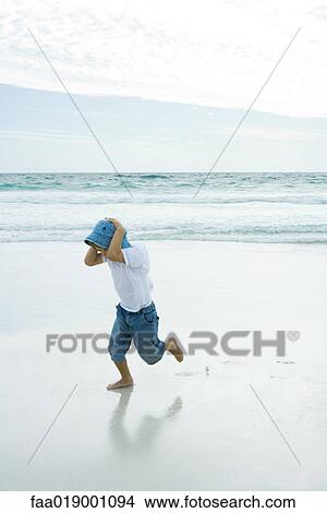 Picture - Child running on beach, holding head. Fotosearch