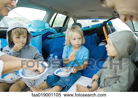 Stock Photography - Children eating meal in back of car. Fotosearch