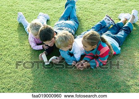 Children lying on grass together, reading View Large Photo Image Stock Image - Children lying on grass together, reading. Fotosearch