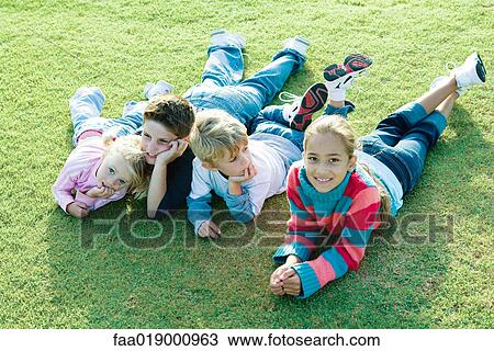 Children lying on grass together View Large Photo Image Stock Image - Children lying on grass together. Fotosearch