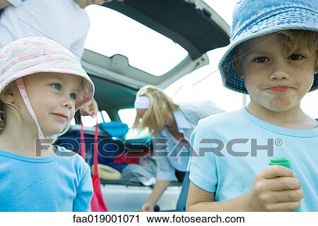 Stock Image - Children standing in front of trunk of car. Fotosearch