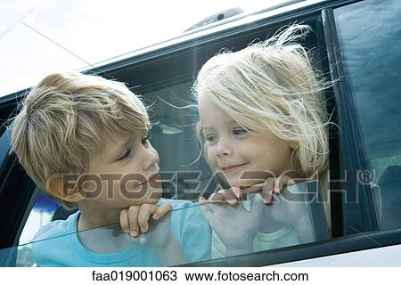 Stock Image - Children sticking heads out of car window. Fotosearch