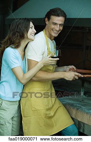 Couple standing by barbecue, woman holding glass of wine, both laughing View Large Photo Image Stock Image - Couple standing by barbecue, woman holding glass of wine, both laughing. Fotosearch