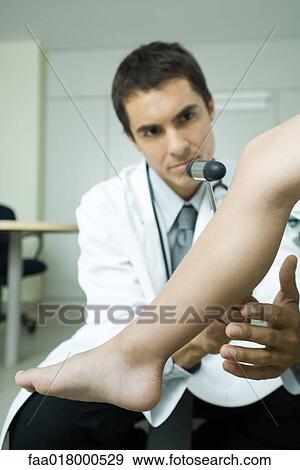 Stock Photo - Doctor checking boy's reflexes with reflex hammer, close-up. Fotosearch