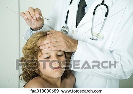 Stock Photo - Doctor feeling boy's forehead and holding thermometer. Fotosearch