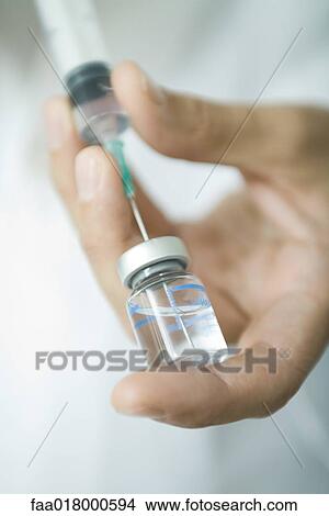 Picture - Doctor filling syringe from bottle. Fotosearch