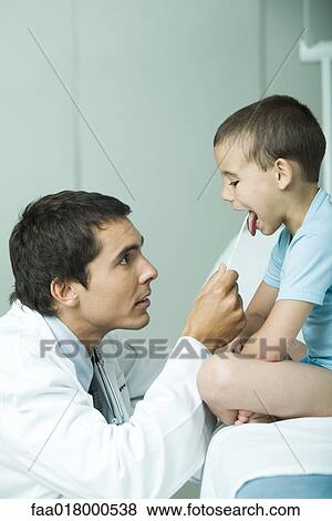 Stock Photo - Doctor holding down boy's tongue with tongue depressor. Fotosearch