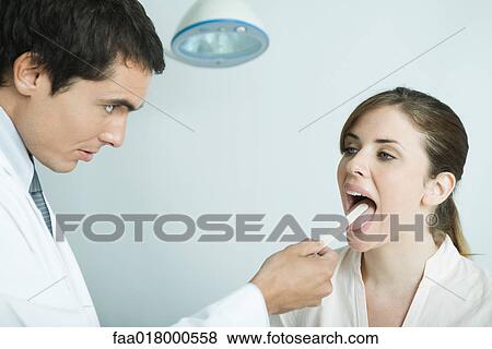 Stock Photo - Doctor holding down woman's tongue with tongue depressor. Fotosearch