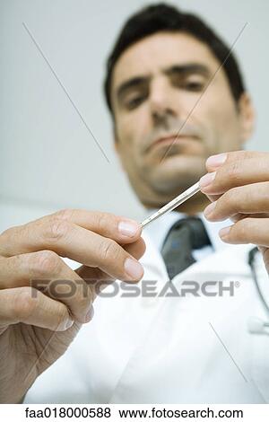 Doctor holding thermometer, low angle view View Large Photo Image Stock Photo - Doctor holding thermometer, low angle view. Fotosearch