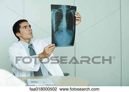 Stock Image - Doctor holding up x-ray. Fotosearch