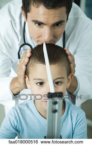 Stock Photograph - Doctor measuring boy during check-up. Fotosearch