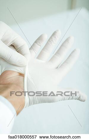 Stock Photo - Doctor putting on latex gloves, close-up. Fotosearch