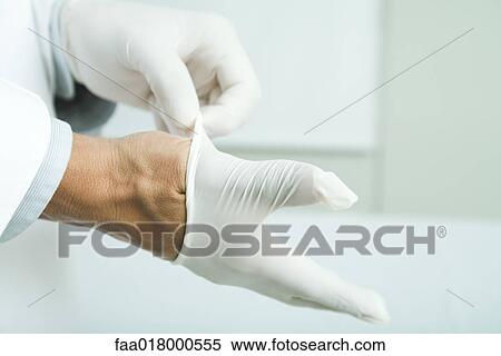 Stock Photography - Doctor putting on latex gloves, close-up. Fotosearch