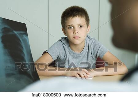 Doctor sitting across from boy, looking at x-ray View Large Photo Image Stock Image - Doctor sitting across from boy, looking at x-ray. Fotosearch