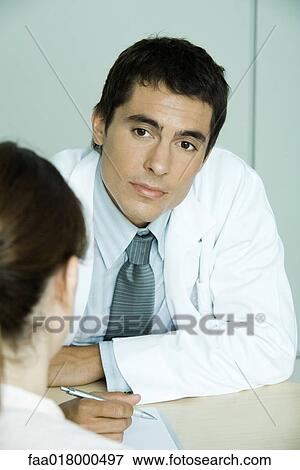 Doctor sitting across from female patient View Large Photo Image Stock Photo - Doctor sitting across from female patient. Fotosearch