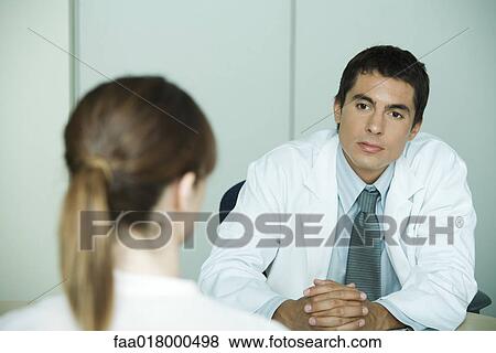 Stock Photo - Doctor sitting across from female patient. Fotosearch
