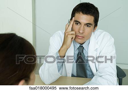 Stock Photography - Doctor sitting across from female patient. Fotosearch