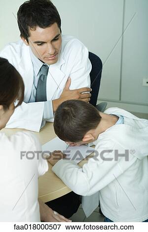 Doctor sitting with boy and woman, boy drawing on paper, high angle view View Large Photo Image Stock Photo - Doctor sitting with boy and woman, boy drawing on paper, high angle view. Fotosearch