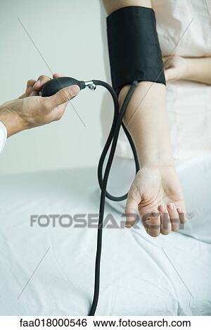Stock Photograph - Doctor taking woman's blood pressure, close-up. Fotosearch