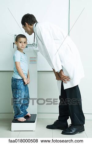 Stock Photo - Doctor weighing boy during check-up. Fotosearch