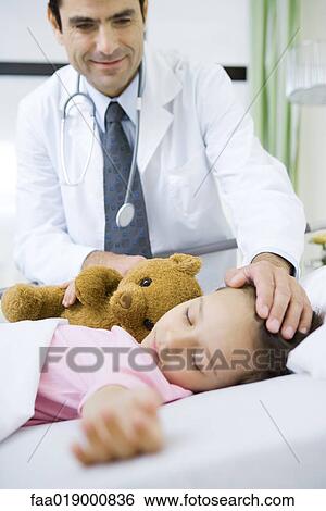 Stock Photograph - Doctor with hand on sleeping child's head, smiling. Fotosearch