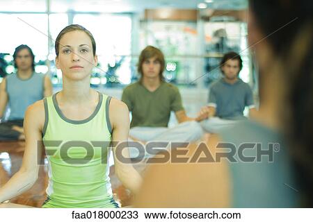 Stock Image - Exercise class sitting in yoga position. Fotosearch