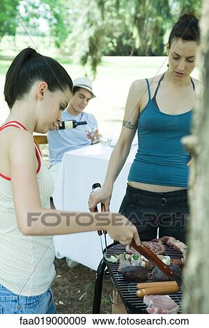 Stock Photo - Family grilling meat on barbecue. Fotosearch
