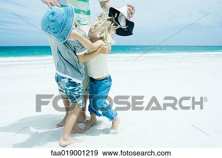 Family on beach, boy and girl reaching for each other in front of father View Large Photo Image Stock Photo - Family on beach, boy and girl reaching for each other in front of father. Fotosearch