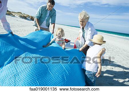 Family on beach, spreading blanket View Large Photo Image Stock Photography - Family on beach, spreading blanket. Fotosearch