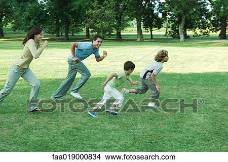 Picture - Family outdoors, running across grass together. Fotosearch