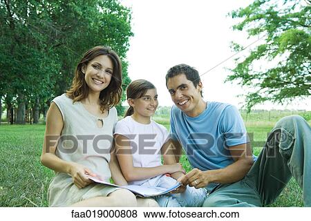 Family sitting outdoors, reading together View Large Photo Image Stock Photo - Family sitting outdoors, reading together. Fotosearch